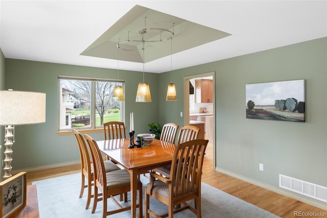 dining room with a raised ceiling and light hardwood / wood-style flooring