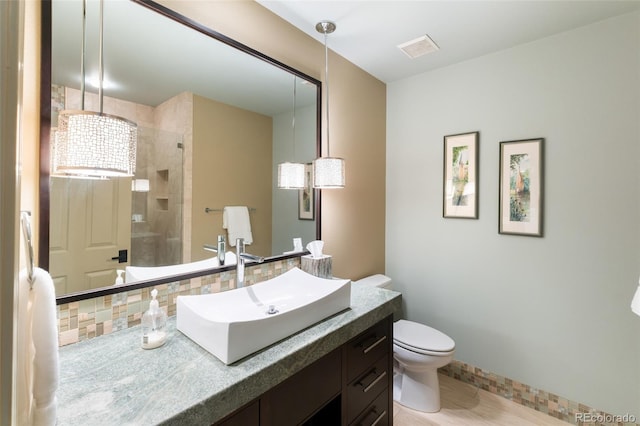 bathroom featuring vanity, toilet, an enclosed shower, and decorative backsplash