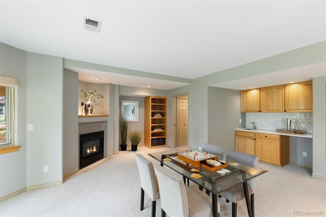 carpeted dining space with built in shelves, a fireplace, and indoor bar