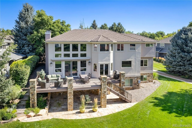 back of house with an outdoor living space, a deck, and a lawn