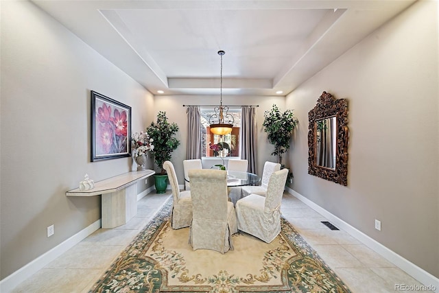 dining room featuring light tile floors and a raised ceiling