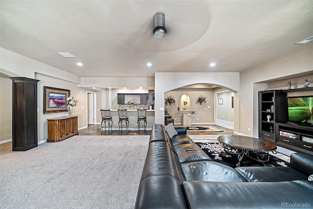 carpeted living room with ceiling fan and a textured ceiling