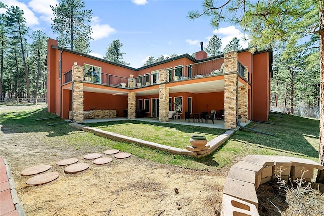 rear view of house featuring a balcony, a lawn, and a patio