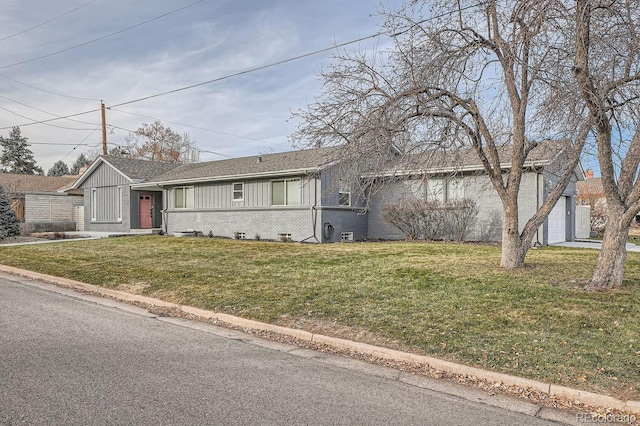 single story home featuring board and batten siding, a garage, brick siding, and a front lawn