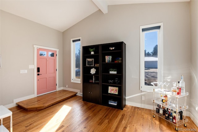 entryway with vaulted ceiling with beams, plenty of natural light, and wood finished floors