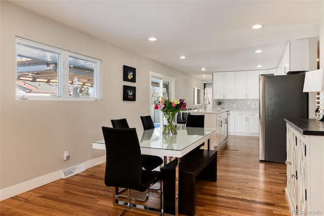 dining room featuring visible vents, baseboards, wood finished floors, and recessed lighting