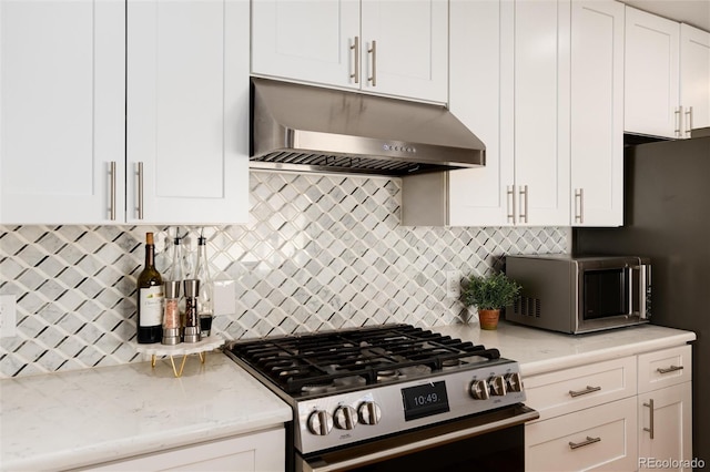 kitchen featuring light stone counters, under cabinet range hood, white cabinetry, appliances with stainless steel finishes, and tasteful backsplash