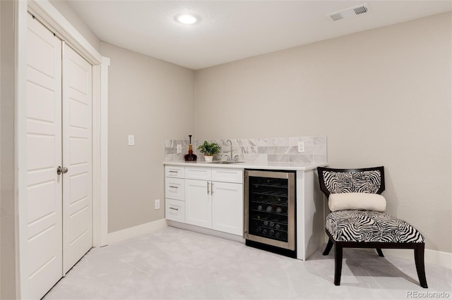 bar with beverage cooler, light carpet, a sink, visible vents, and indoor wet bar