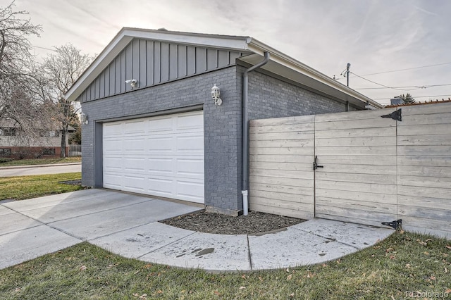 garage featuring concrete driveway and fence