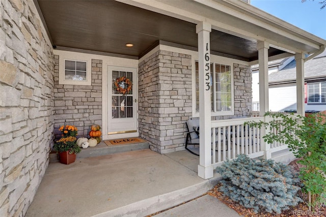 view of exterior entry with covered porch and stone siding