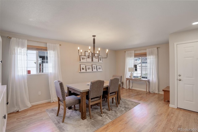 dining space featuring light wood-style flooring, an inviting chandelier, and baseboards