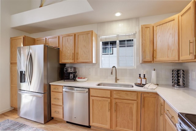 kitchen featuring a sink, light countertops, appliances with stainless steel finishes, light brown cabinetry, and backsplash
