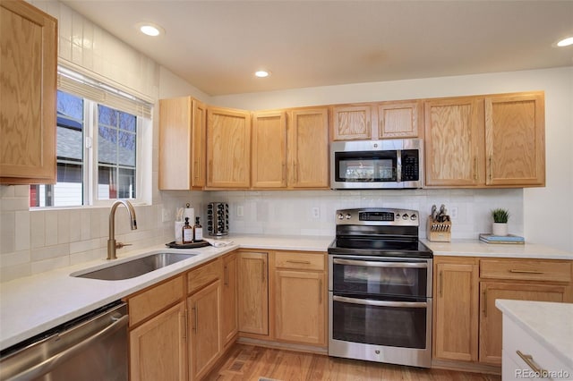 kitchen featuring tasteful backsplash, recessed lighting, light countertops, appliances with stainless steel finishes, and a sink