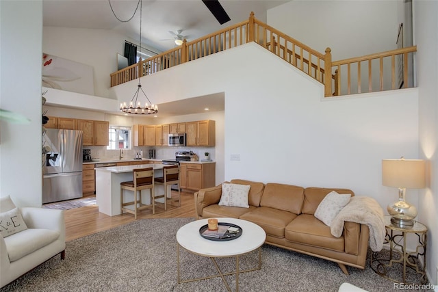 living area featuring light wood-style floors, high vaulted ceiling, and ceiling fan