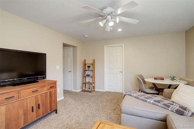 living area with light colored carpet, ceiling fan, and baseboards