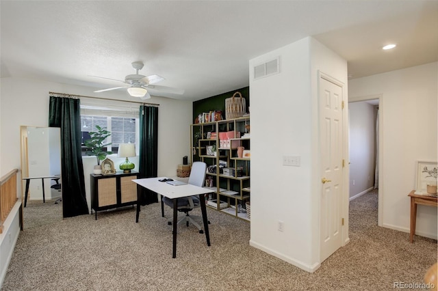 office space featuring light carpet, baseboards, a ceiling fan, and visible vents