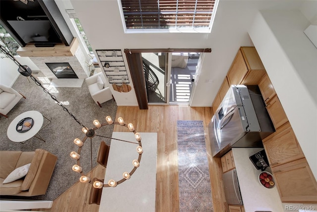 living room featuring a glass covered fireplace, a high ceiling, wood finished floors, and a healthy amount of sunlight