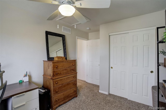 bedroom with a closet, light carpet, attic access, visible vents, and ceiling fan