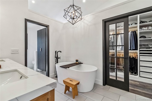 7388 S Ireland Cir, Centennial, CO 80016 - bathroom featuring a freestanding bath, double vanity, a chandelier, tile patterned flooring, and a walk in closet