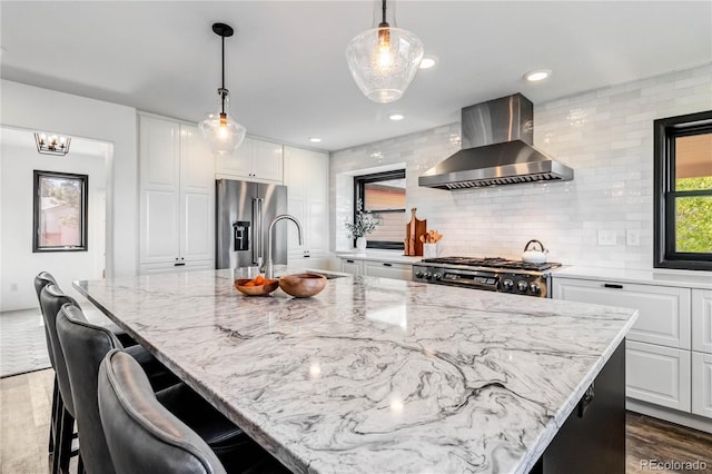 7388 S Ireland Cir, Centennial, CO 80016 - kitchen with wall chimney exhaust hood, high quality fridge, dark wood-type flooring, light stone countertops, and white cabinetry