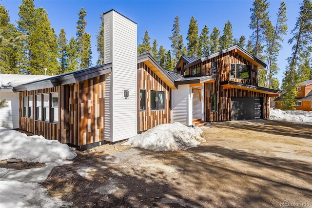 209 American Way, Breckenridge, CO 80424 - view of front facade featuring a chimney, a garage, a metal roof, dirt driveway, and a standing seam roof