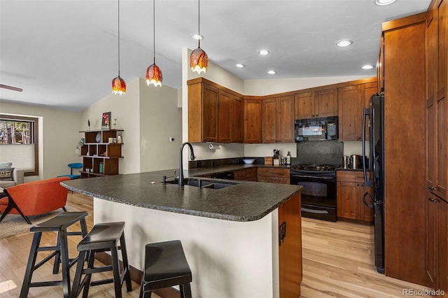 209 American Way, Breckenridge, CO 80424 - kitchen with black appliances, a peninsula, light wood-style flooring, vaulted ceiling, and a kitchen breakfast bar