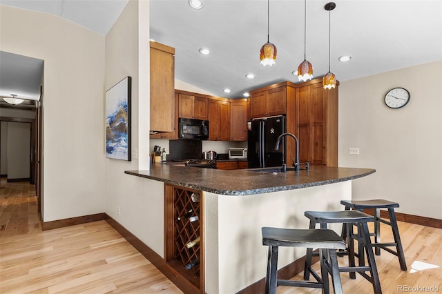209 American Way, Breckenridge, CO 80424 - kitchen with black appliances, lofted ceiling, a breakfast bar, light wood-style floors, and pendant lighting