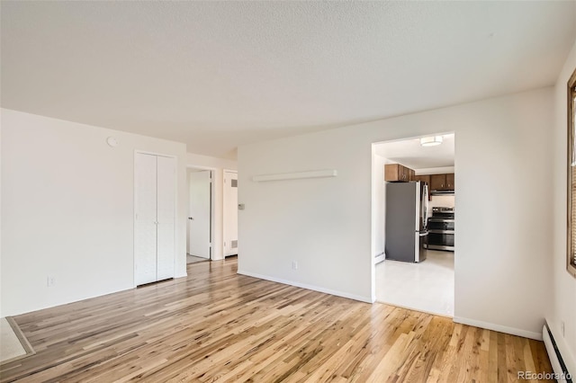 unfurnished room featuring a baseboard heating unit, a textured ceiling, and light hardwood / wood-style flooring