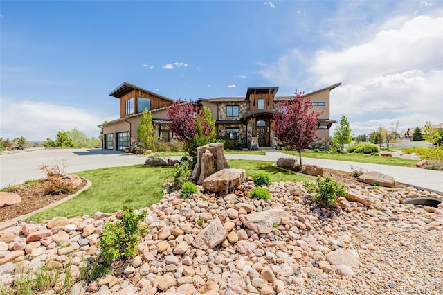 modern home featuring an attached garage, driveway, and stone siding