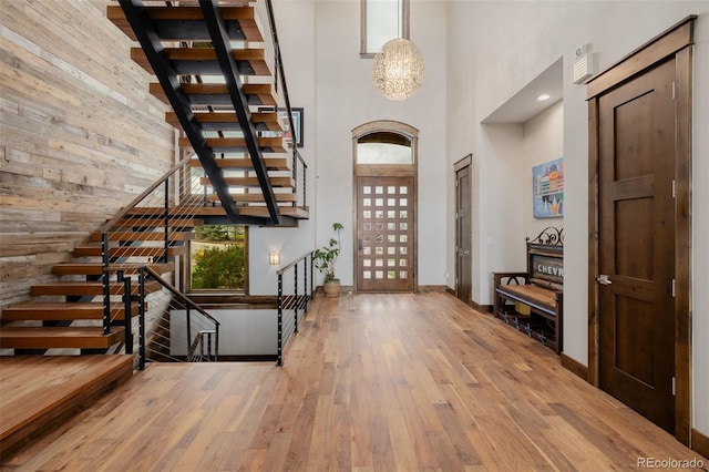 foyer with wood walls, baseboards, a high ceiling, stairs, and hardwood / wood-style floors