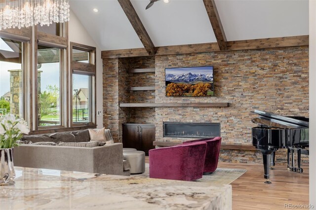 living room featuring a stone fireplace, recessed lighting, wood finished floors, and vaulted ceiling with beams