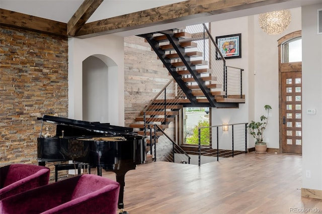 living area with plenty of natural light, a high ceiling, stairway, and wood finished floors