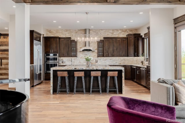 kitchen featuring light wood-type flooring, decorative backsplash, appliances with stainless steel finishes, and dark brown cabinets