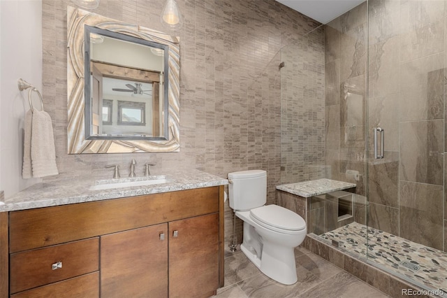 full bathroom featuring tile walls, a shower stall, vanity, toilet, and marble finish floor