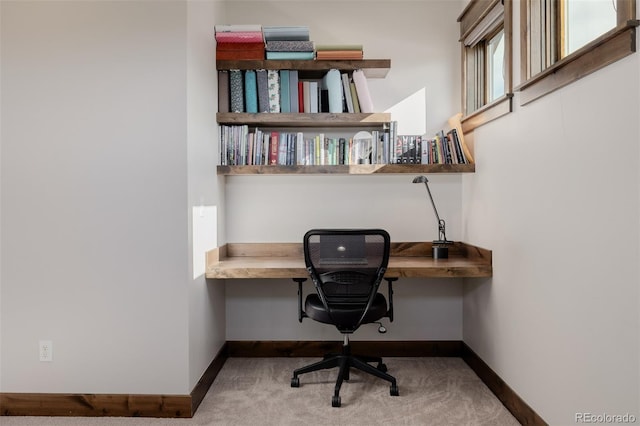 carpeted office space featuring baseboards and built in desk