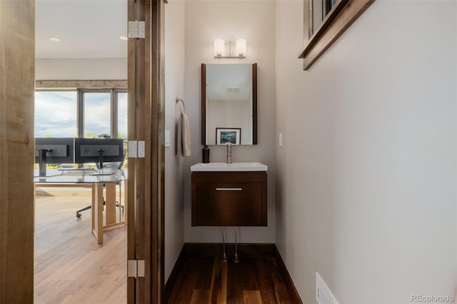 bathroom with baseboards, wood finished floors, and vanity
