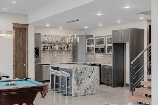 bar with hanging light fixtures, finished concrete flooring, decorative backsplash, billiards, and bar area