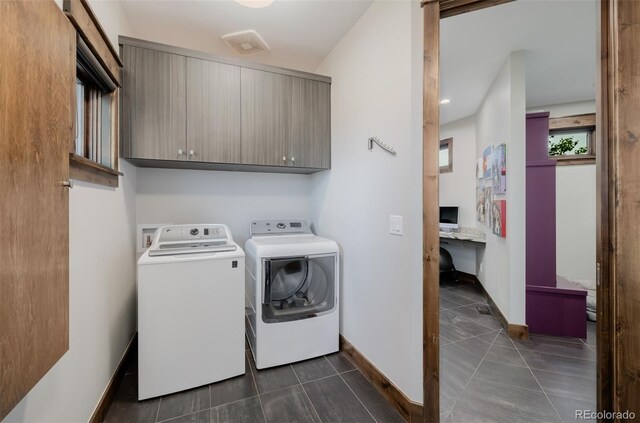clothes washing area with dark tile patterned floors, cabinet space, baseboards, and washer and dryer