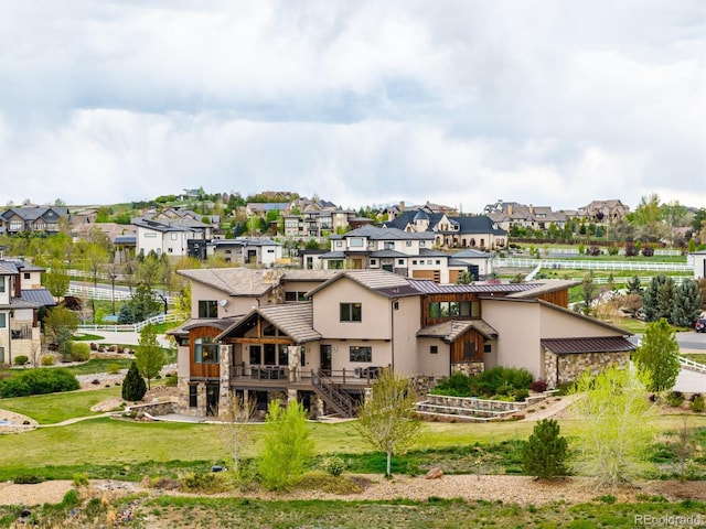 back of property featuring a residential view, stone siding, stucco siding, a standing seam roof, and metal roof