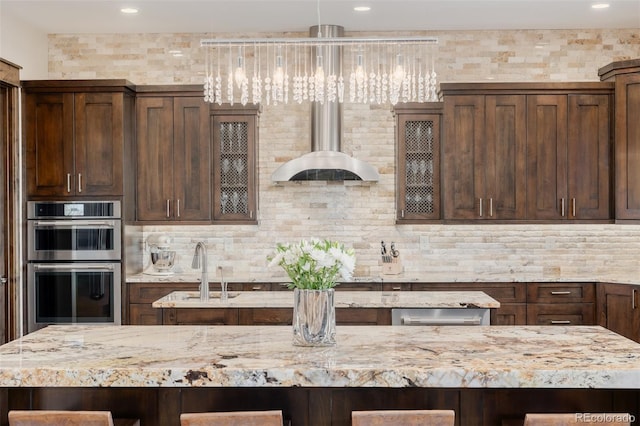 kitchen with double oven, a sink, light stone countertops, and tasteful backsplash
