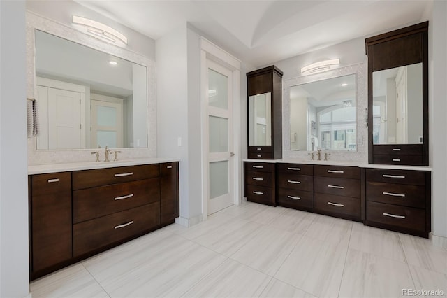 full bath with baseboards, two vanities, and a sink