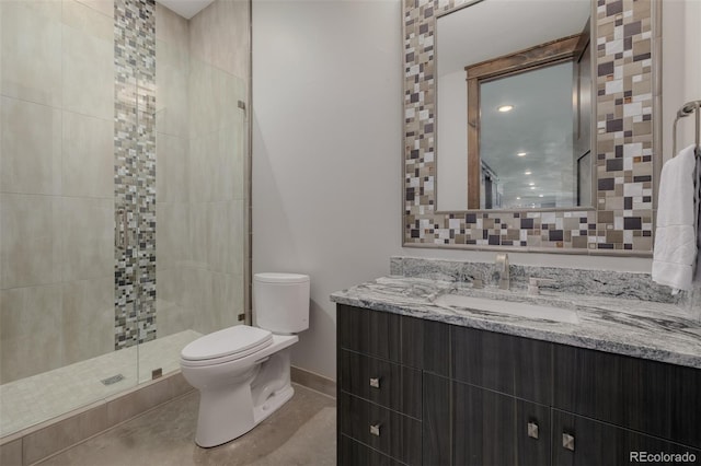 bathroom with vanity, baseboards, a stall shower, and toilet