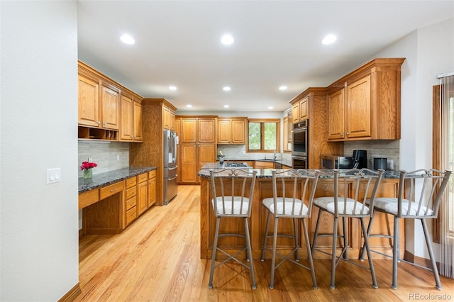 3935 Pierson St, Wheat Ridge, CO 80033 - kitchen with appliances with stainless steel finishes, built in study area, light wood-style flooring, a peninsula, and dark stone counters