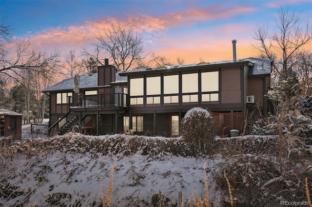 snow covered back of property with a deck