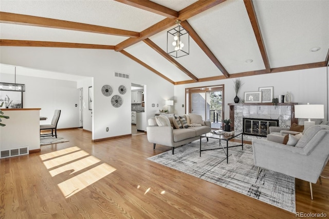 living room featuring beamed ceiling, light wood-type flooring, a fireplace, and high vaulted ceiling