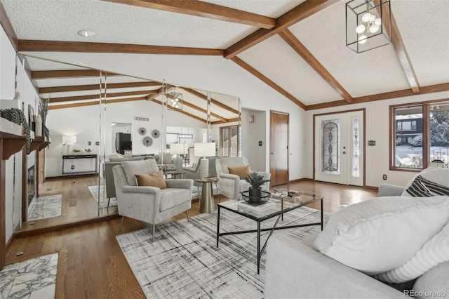 living room featuring wood-type flooring, lofted ceiling with beams, a textured ceiling, and an inviting chandelier