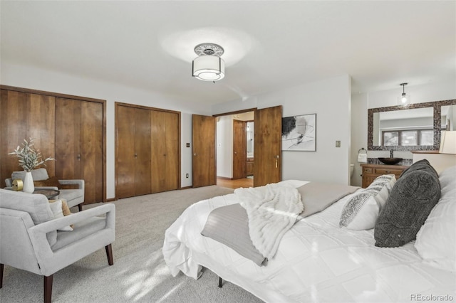 bedroom with light colored carpet and two closets