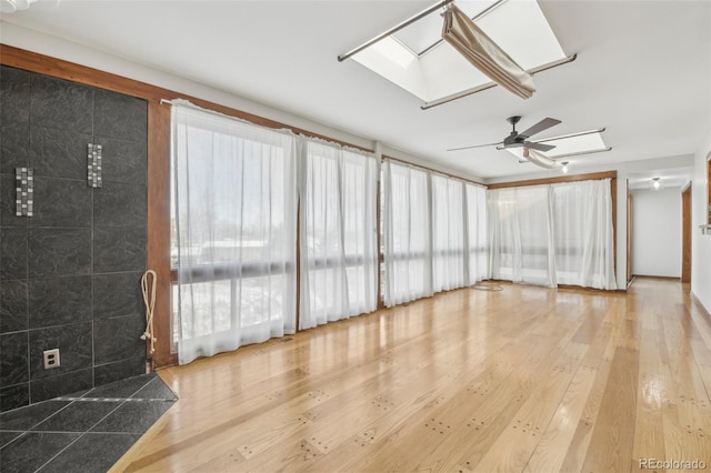 unfurnished sunroom with a skylight and ceiling fan