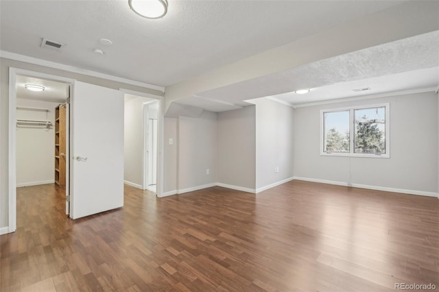 basement with a textured ceiling, ornamental molding, and dark wood-type flooring