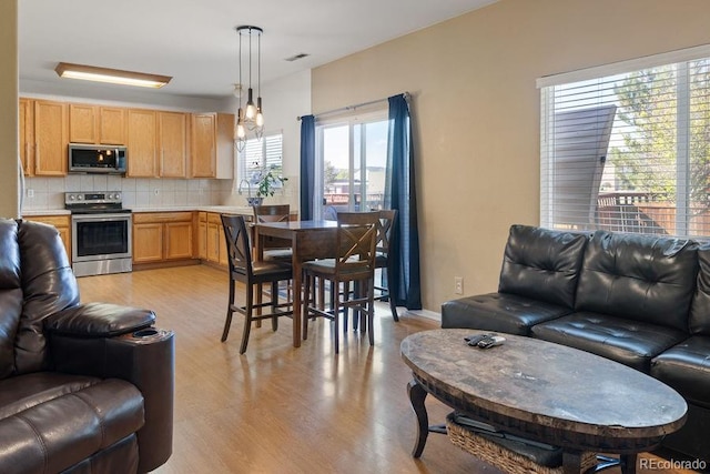 kitchen featuring pendant lighting, a healthy amount of sunlight, stainless steel appliances, and backsplash